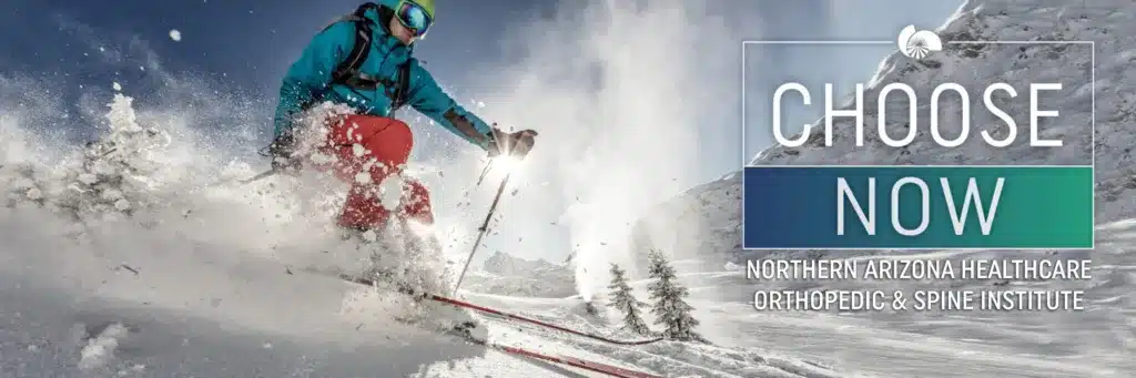 A skier speeding down a snowy mountain slope, kicking up snow as they maneuver. The image promotes Northern Arizona Healthcare Orthopedic & Spine Institute with the text “Choose Now” on the right side.