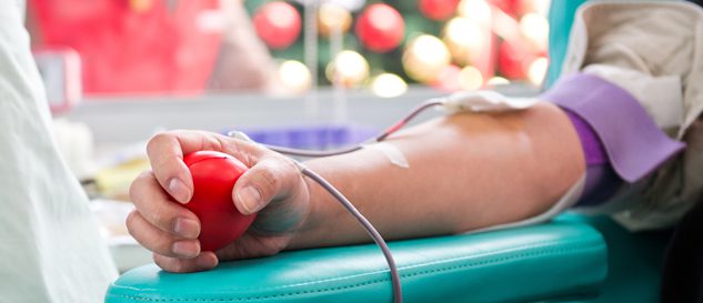 Person donating blood while squeezing a red stress ball