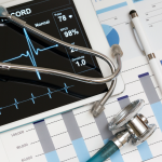 Digital heart rate monitor on tablet with stethoscope and medical charts