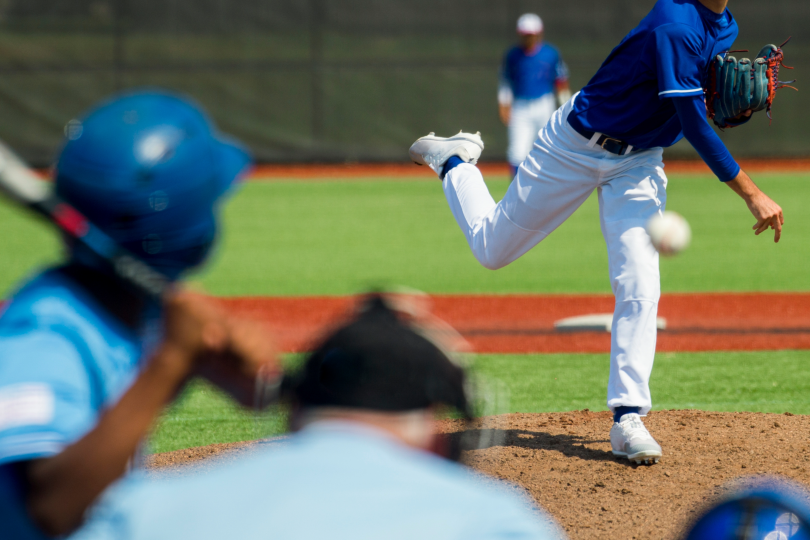 Baseball pitcher throwing a pitch toward a batter during a game.