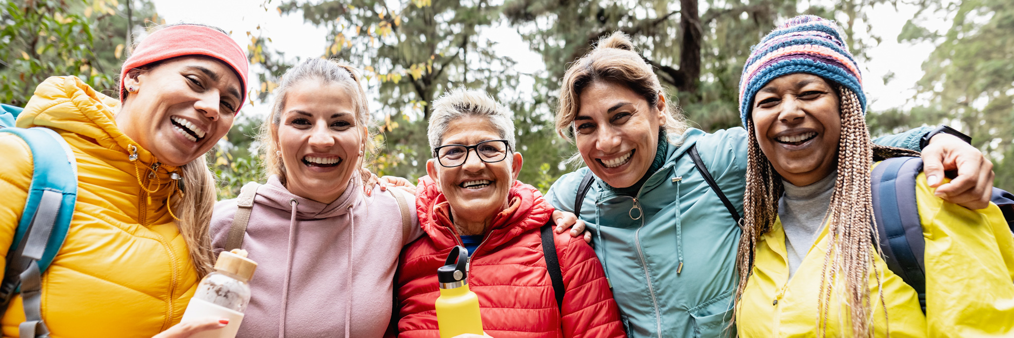 Group of women with different ages and ethnicities having fun walking in the woods - Adventure and travel people concept