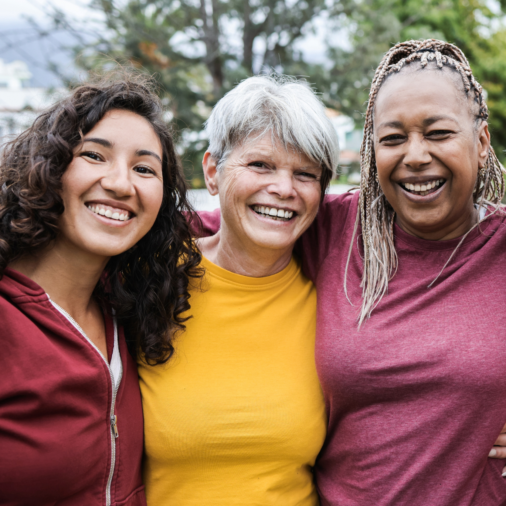 Three smiling women facing the the camera wearing colorful clothing